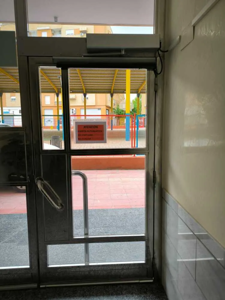 Puerta automática abatible en un edificio de viviendas